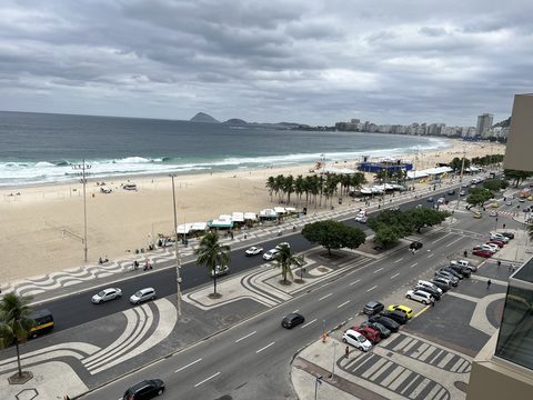 A beach, its wave-patterned promenade, and the avenue seen from above