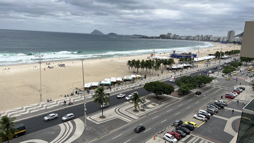 A beach, its wave-patterned promenade, and the avenue seen from above