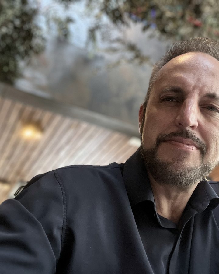 Vaughn Bullard in a dark sweater, taking a selfie indoors at a restaurant