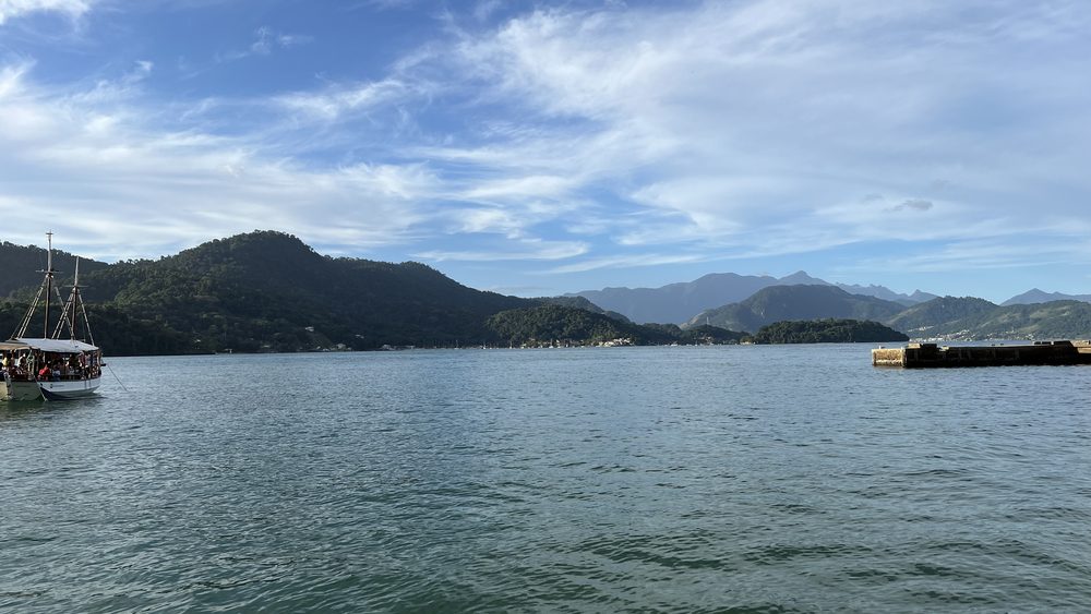 A calm bay with mountains and a sailboat