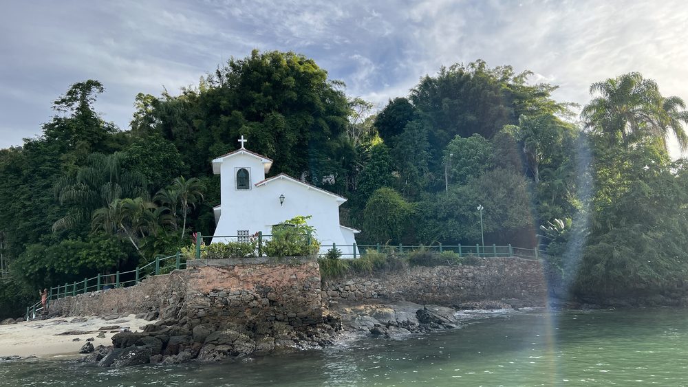 A small white chapel on the shore of a green island