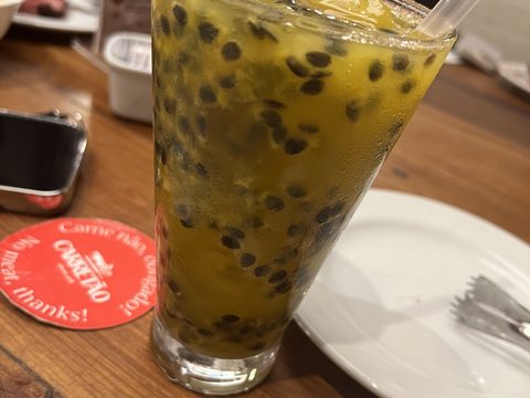 A passion-fruit drink in a tall glass on a wooden table
