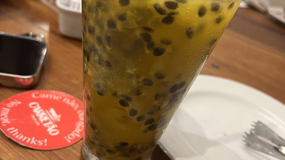 A passion-fruit drink in a tall glass on a wooden table
