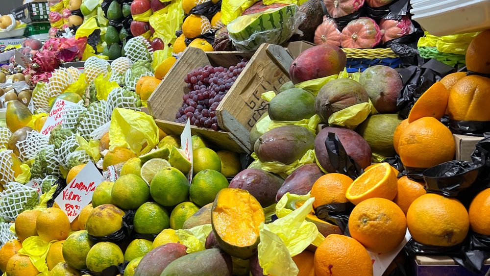 A market stall stacked with oranges, mangoes, pitaya and other fruit