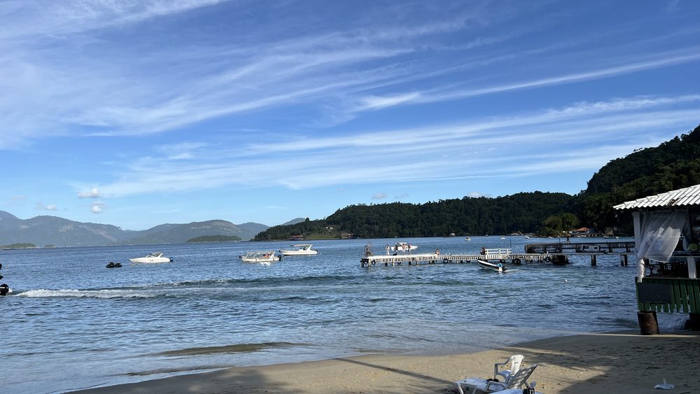 A beach, a pier and boats under a blue sky
