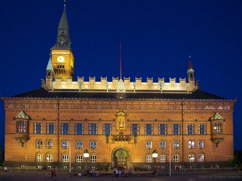 Copenhagen City Hall lit up at night with its clock tower