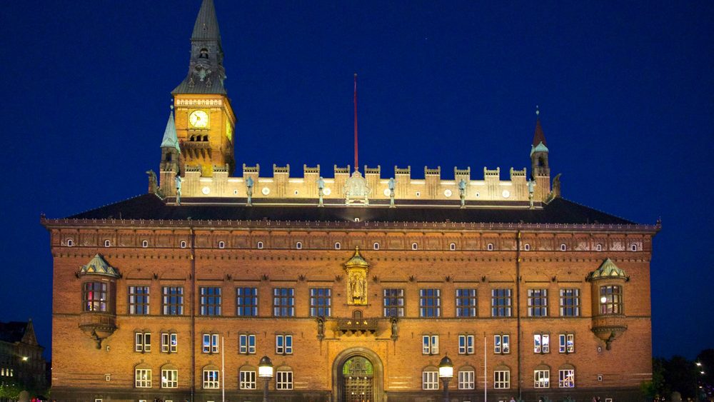 Copenhagen City Hall lit up at night with its clock tower
