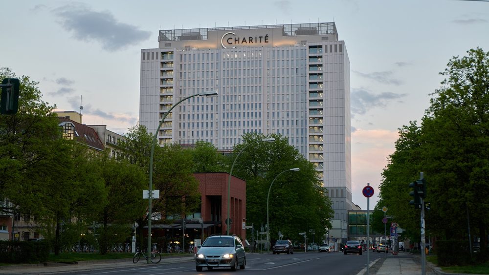 Charite hospital tower in Berlin with a tree-lined street in front