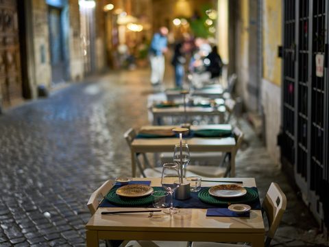 Cafe tables set on a cobbled street in Rome on a summer evening