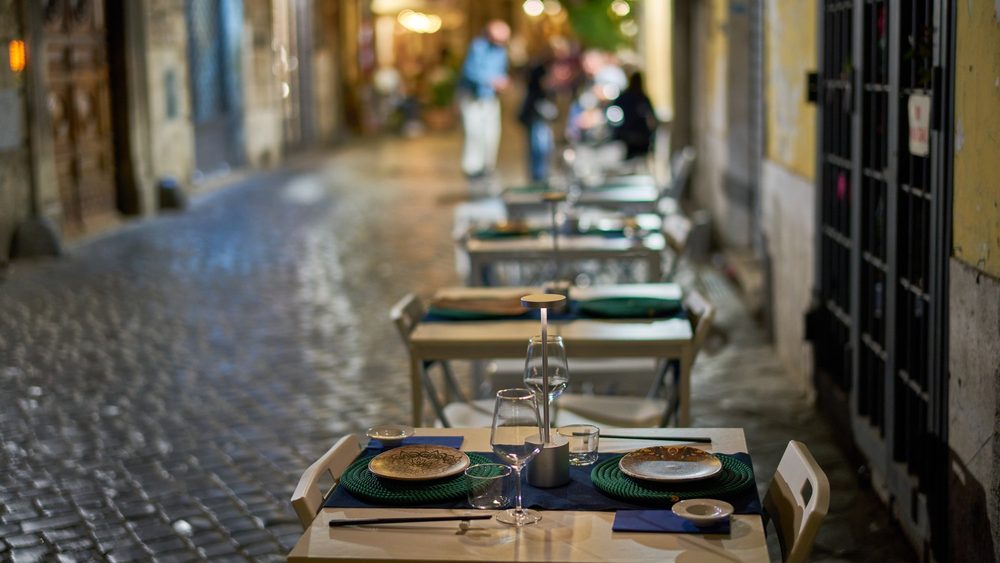 Cafe tables set on a cobbled street in Rome on a summer evening