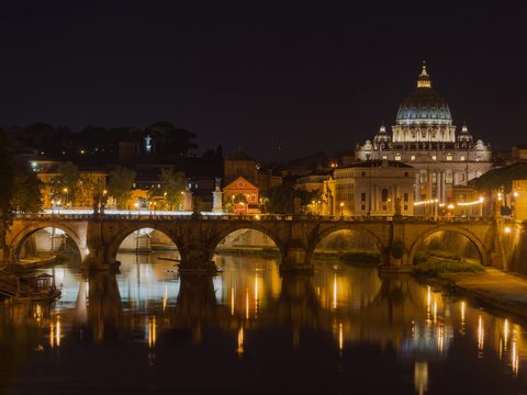 Saint Peter's Basilica and the Sant'Angelo bridge lit up at night in Rome