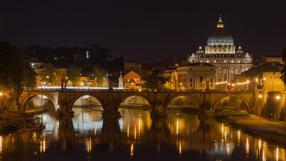 Saint Peter's Basilica and the Sant'Angelo bridge lit up at night in Rome