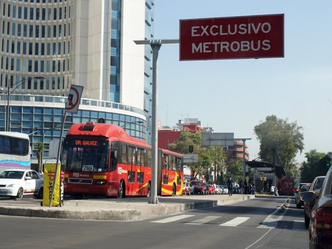 Red Metrobus articulated bus at a dedicated lane station in Mexico City