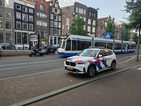 Dutch police car parked by a tram on an Amsterdam street