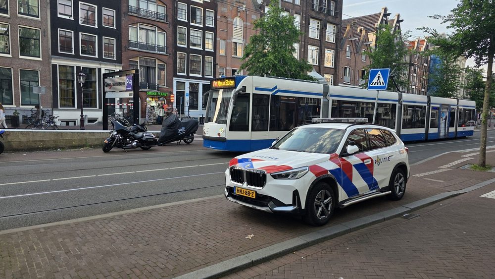 Dutch police car parked by a tram on an Amsterdam street