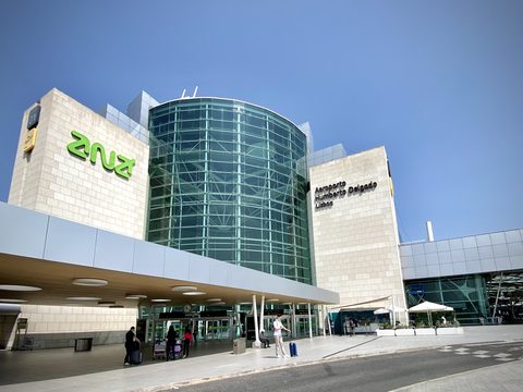 The glass rotunda and entrance of Lisbon Humberto Delgado Airport under a blue sky