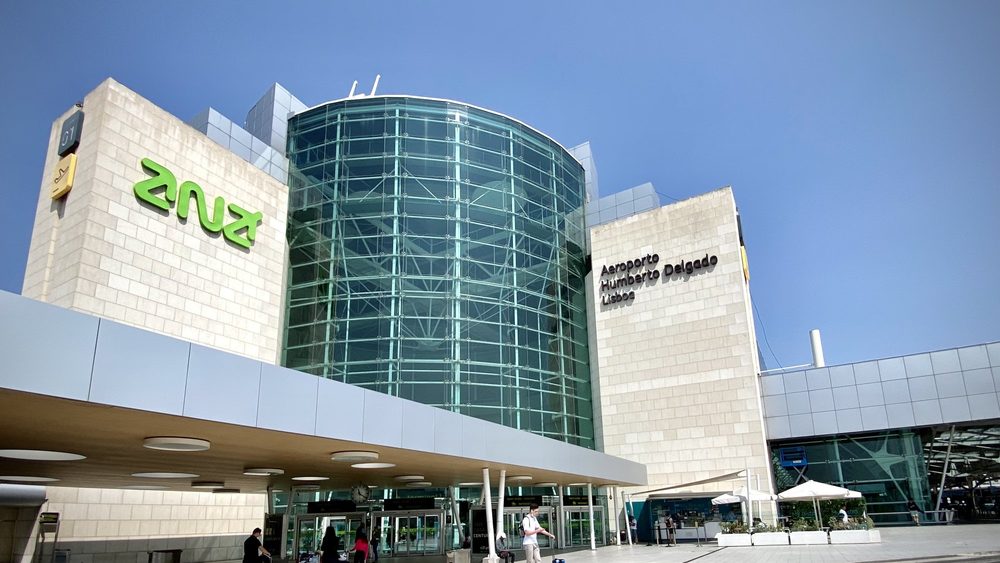 The glass rotunda and entrance of Lisbon Humberto Delgado Airport under a blue sky