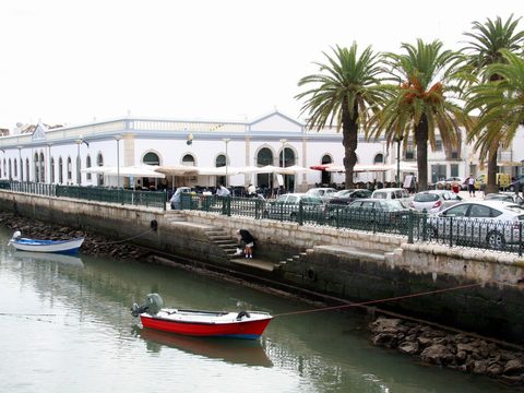 Riverside street with palm trees and boats in Tavira, Algarve
