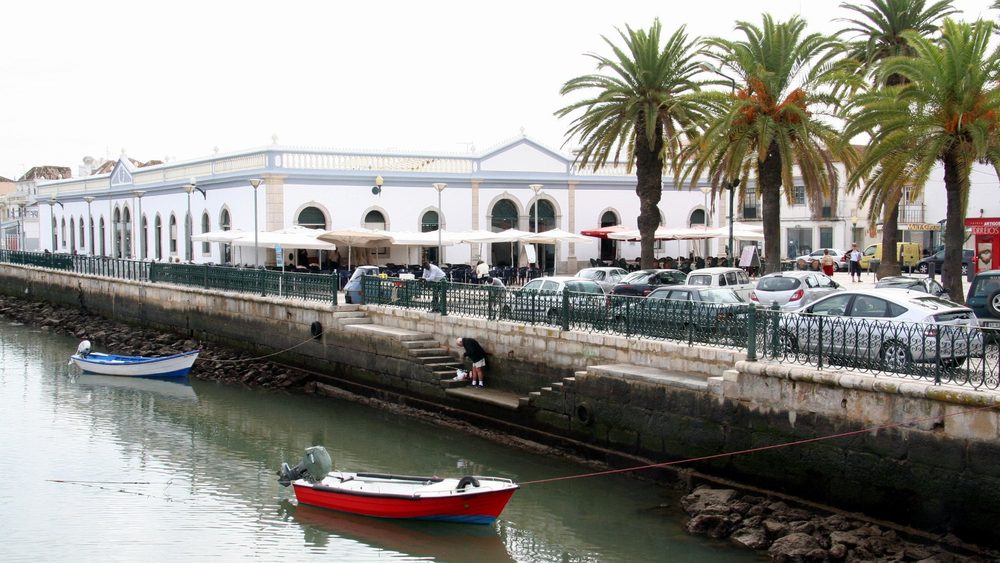 Riverside street with palm trees and boats in Tavira, Algarve