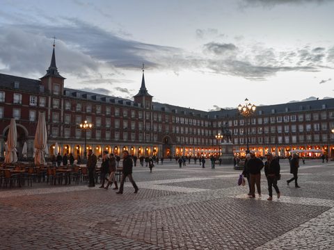 Plaza Mayor in central Madrid with its red arcaded buildings and pedestrians crossing the square