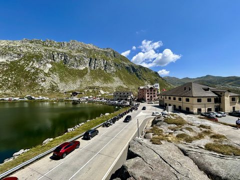 Road over the Saint Gotthard Pass with cars beside the mountain lake