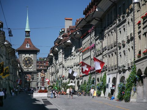Kramgasse in Bern old town with arcades, flags and the Zytglogge