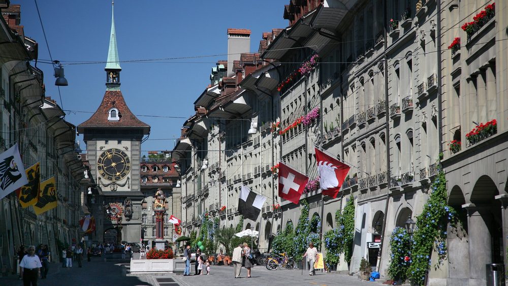 Kramgasse in Bern old town with arcades, flags and the Zytglogge