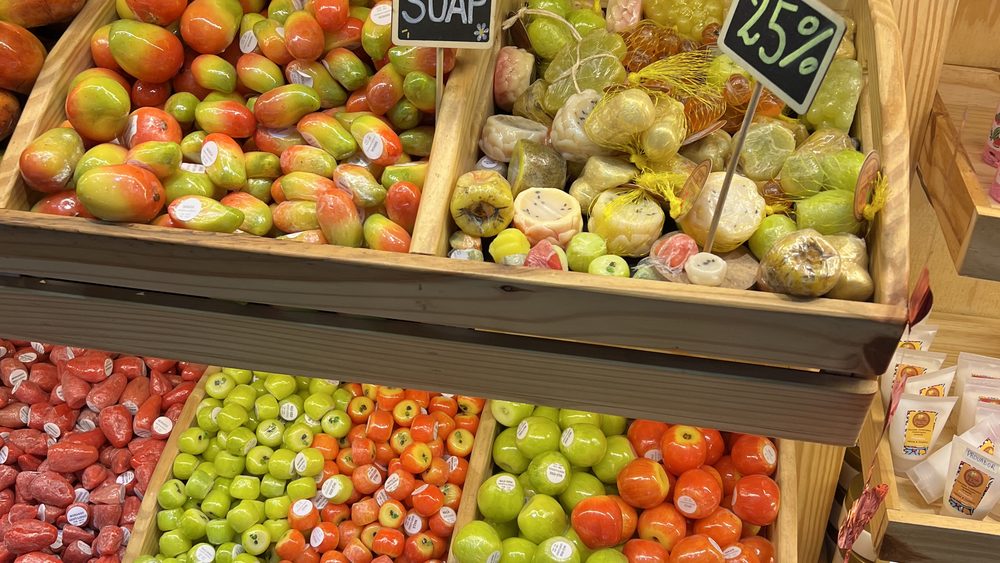 Rows of fruit-shaped handmade soaps on a market display